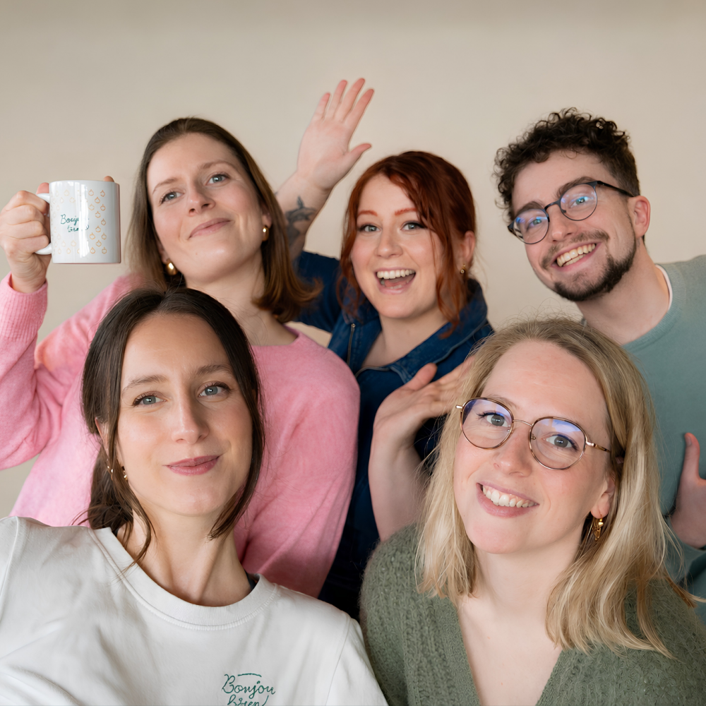 Équipe de l'agence de communication Boujou Bien à Rouen - cinq collègues souriants dans une ambiance chaleureuse et conviviale, reflétant l'esprit de collaboration et de créativité de l'agence.